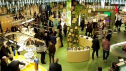 A large booth at the EuroShop 2023 in green with many visitors; copyright: beta-web GmbH