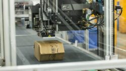 A packaging machine processes a package on a conveyor belt; Copyright: Amazon