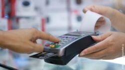 A person is paying with a credit card at an ATM. A receipt is visible.// copyright: akportfolio24/envato