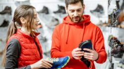 A customer and a sales assistant in the shop are talking about the shoes they are holding.