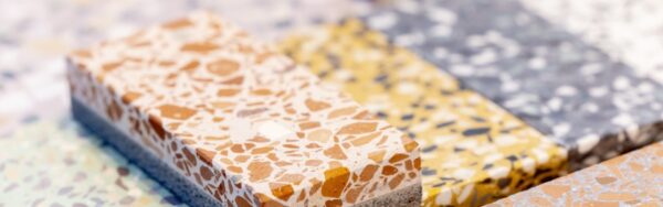 Several samples of terrazzo with differently colored stone fragments, stacked on a presentation surface for materials; copyright: Messe Düsseldorf/A. Wiese