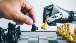 A human hand and a robotic hand move chess pieces on a board; Copyright: Adobe Express, AI-generated