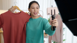 A person presents a red T-shirt to the camera; Copyright: Adobe Express