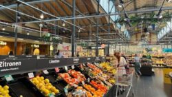 Large fruit and vegetable department with labeled boards and plenty of daylight under an imposing, wooden hall roof with steel beams; copyright: Yvonne Manleitner 