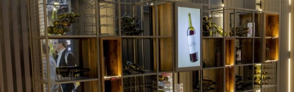 Shelf installation made of metal and wooden cubes with wine bottles on display and integrated screen with digital product presentation; copyright: Messe Düsseldorf/A. Wiese